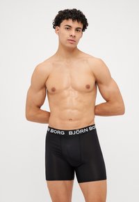 Schwarze Boxershorts mit glatter Textur und elastischem Bund, der den Markennamen "BJÖRN BORG" in weißer Schrift trägt.