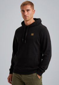 Black hooded sweatshirt made of fleece fabric, featuring a front pouch pocket, drawstring hood, and a small yellow logo on the chest.