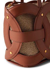 Brown leather handbag with a textured, beige patterned interior. Features prominent circular cutouts and gold hardware accents.