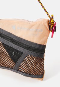 Pfirsichfarbene Tasche mit Netzelementen, grauen Akzenten und einem Kordelzugverschluss. Mit silbernem Logo und kontrastierenden Reißverschlussdetails.