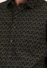 Marineblauwe button-up overhemd met een olijfgroen abstract patroon, borstzak en twee lichtbruine knopen. Merketiket zichtbaar.