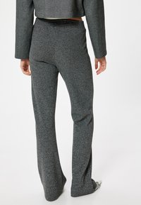 Pantalones grises acampanados hechos de una tela texturizada, con un sutil patrón moteado y una cintura elástica para mayor comodidad.