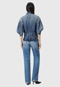 Giubbotto di jeans con vita aderente, maniche a sbuffo e una tonalità di blu sbiadito. Abbinato a jeans a gamba dritta con orli sfrangiati.