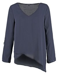 Blouse bleu marine à manches longues avec col en V et ourlet asymétrique, en tissu léger et semi-transparent.