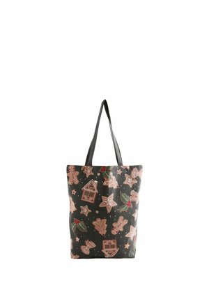 Sac cabas avec anses noires, décoré de biscuits en pain d'épices, d'étoiles, de feuilles de houx et de formes de bonbons sur un fond sombre.