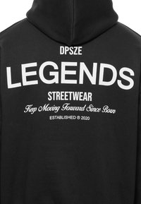 Sort hættebluse med stor hvid tekst på ryggen: "DPSZE LEGENDS STREETWEAR" og "Keep Moving Forward Since Born." Etableret 2020.