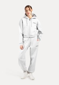 Grijze cropped zip-up hoodie met een voorzak en bijpassende sweatpants. Gemaakt van zachte stof met elastische manchetten en tailleband.