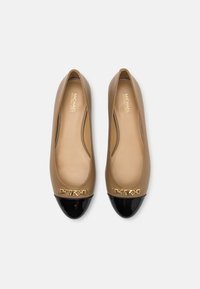 Ballerine beige con punta a contrasto nera lucida, dettaglio in metallo dorato sulla punta e tomaia in pelle liscia. L'interno presenta una soletta beige imbottita.