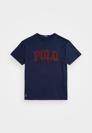 Granatowa koszulka z krótkim rękawem z napisem „POLO RALPH LAUREN” dużymi czerwonymi literami na piersi oraz małym pomarańczowym logo gracza polo na dolnym brzegu.