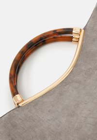 Tote bag met een grijze gestructureerde stof en een handvat van plastic met een tortoisepatroon, en gouden metalen accenten.