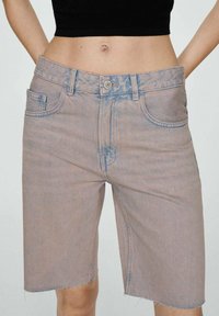 Denim šortsevi u izblijedjeloj ružičastoj boji s visokim strukom, pet džepova, zatvaranjem na gumb te grubljim rubom. Tekstil ima mekan, istrošen izgled.