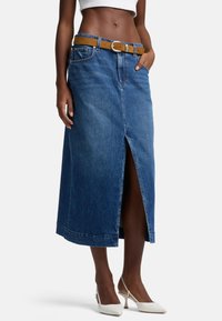 Jupe maxi en denim avec une fente à l'avant, de couleur bleue, dotée d'une ceinture marron et de poches. Texture lisse avec une coupe classique.