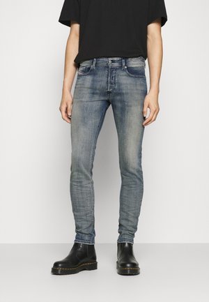 Skinny-fit denim jeans in lichtblauw met een vervaagde afwerking, vijf zakken en zilverkleurige hardware. Gecombineerd met een zwart oversized t-shirt en zwarte laarzen.