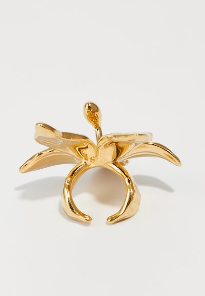 Bague de couleur or avec un motif floral aux pétales courbés, texture lisse et un bandeau ouvert. Forme remarquable évoquant une fleur en pleine floraison.