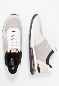 Sportowe sneakersy z siateczkowym i syntetycznym wierzchem w kolorze szarym, czarnym i białym. Posiadają gumową podeszwę i różowo-złote akcenty.