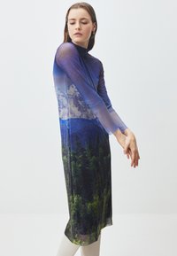 Abito lungo trasparente con maniche lunghe, caratterizzato da una stampa di paesaggio montano in tonalità di blu e verde, con un corpetto aderente e una silhouette fluida.