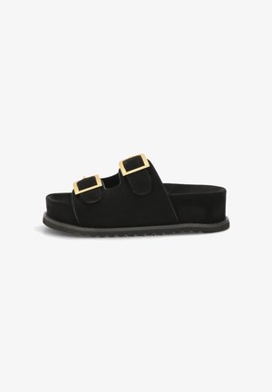 Sandalia tipo slide negra con dos tiras ajustables con hebillas cuadradas doradas y suela plana y texturizada.