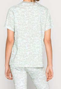 Ljust blå t-shirt med ett mjukt, prickigt mönster i grått. Kort ärm, rund halsringning och en avslappnad passform, tillverkad av ett mjukt material.