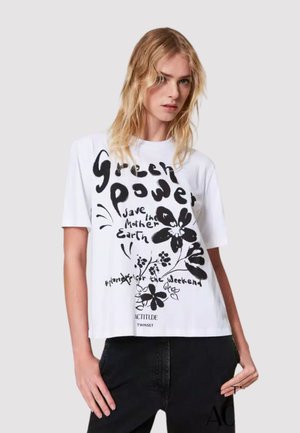T-shirt bianco in cotone con grafiche floreali nere e testo che recita "Green Power Save the Mother Earth" sul davanti. Design cropped.