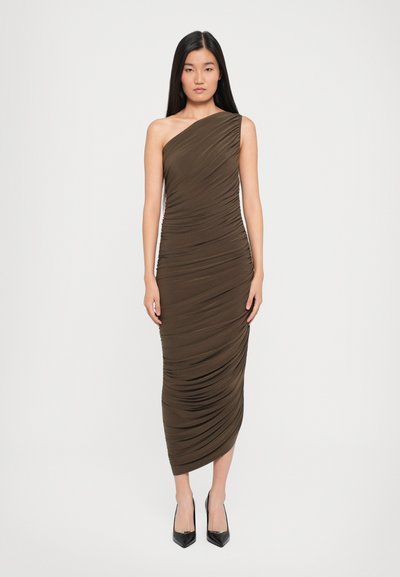 Asymmetrisches braunes Midi-Kleid aus gerafftem Stoff, mit einem schulterfreien Träger und einer figurschmeichelnden Silhouette. Schwarze Absätze runden den Look ab.