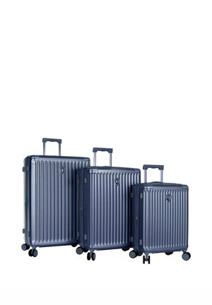 Trois valises rigides bleu marine avec poignées télescopiques et quatre roues, disposées de la plus grande à la plus petite sur fond blanc.