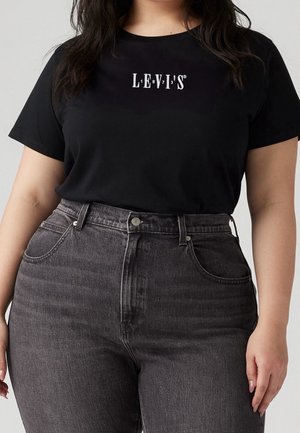 Sort bomulds-T-shirt med hvid "LEVI'S"-logo, stylet med højtaljede grå denimjeans med fem lommer og knaplukning.