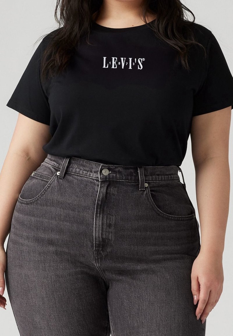 T-shirt en coton noir avec logo blanc "LEVI'S", associé à un jean en denim gris taille haute avec cinq poches et fermeture à boutons.