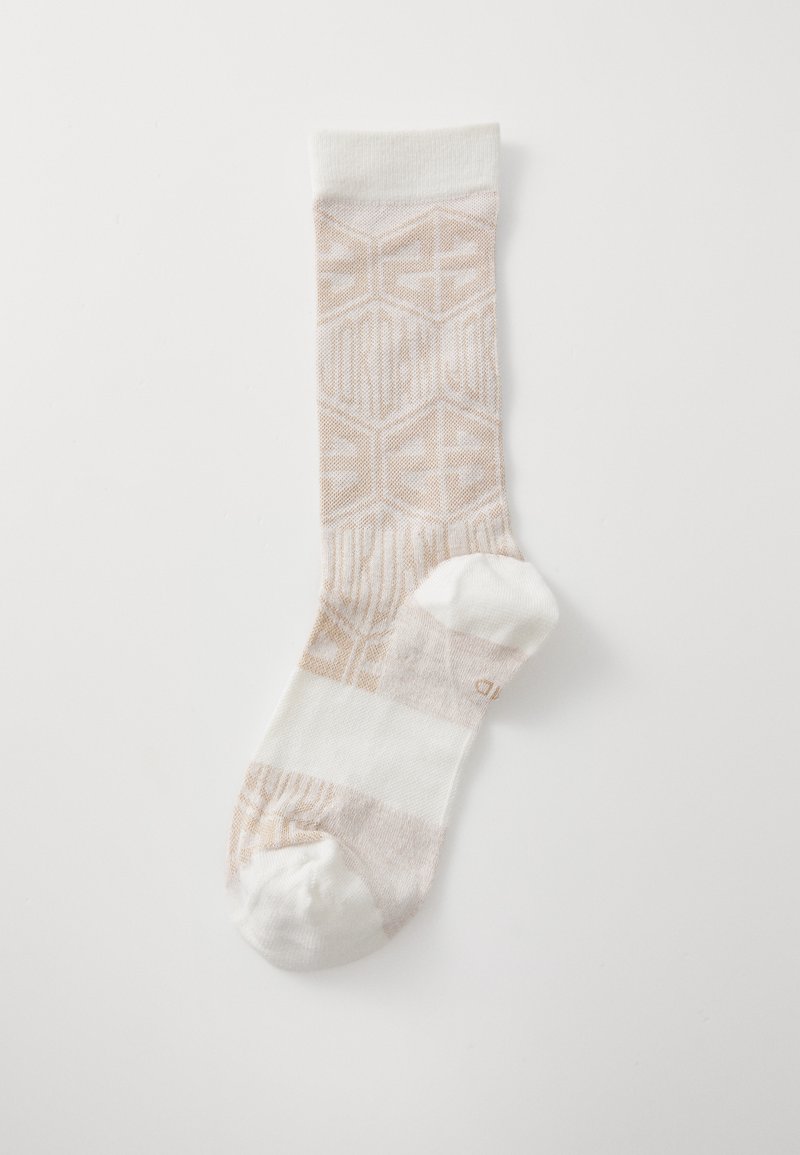 Calcetines beige claro con un patrón geométrico y logo, que presentan una sección blanca a rayas en la puntera y el puño superior. Material de mezcla de algodón.