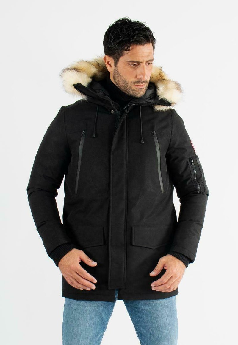 Parka noire pour homme avec une capuche doublée en fourrure, poches zippées sur la poitrine, poches à rabat à l'avant et poignets côtelés. Dispose d'un cordon de serrage ajustable.