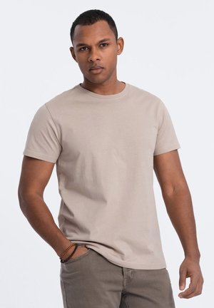 Tričko s krátkým rukávem a kulatým výstřihem v světle béžové barvě z bavlny, s přiléhavým střihem a hladkou texturou. V páru se světlými kalhotami.