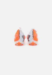 Soccer cleats featuring a white synthetic upper, orange accents, and a textured finish. Includes orange studs for traction on grass surfaces.