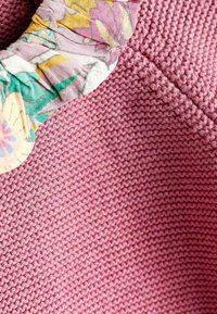 Violetit kudottu kangas, jossa on strukturoitu kuvio, sisältää vaaleita kukkakankaita reunalla, tuoden kontrastia.