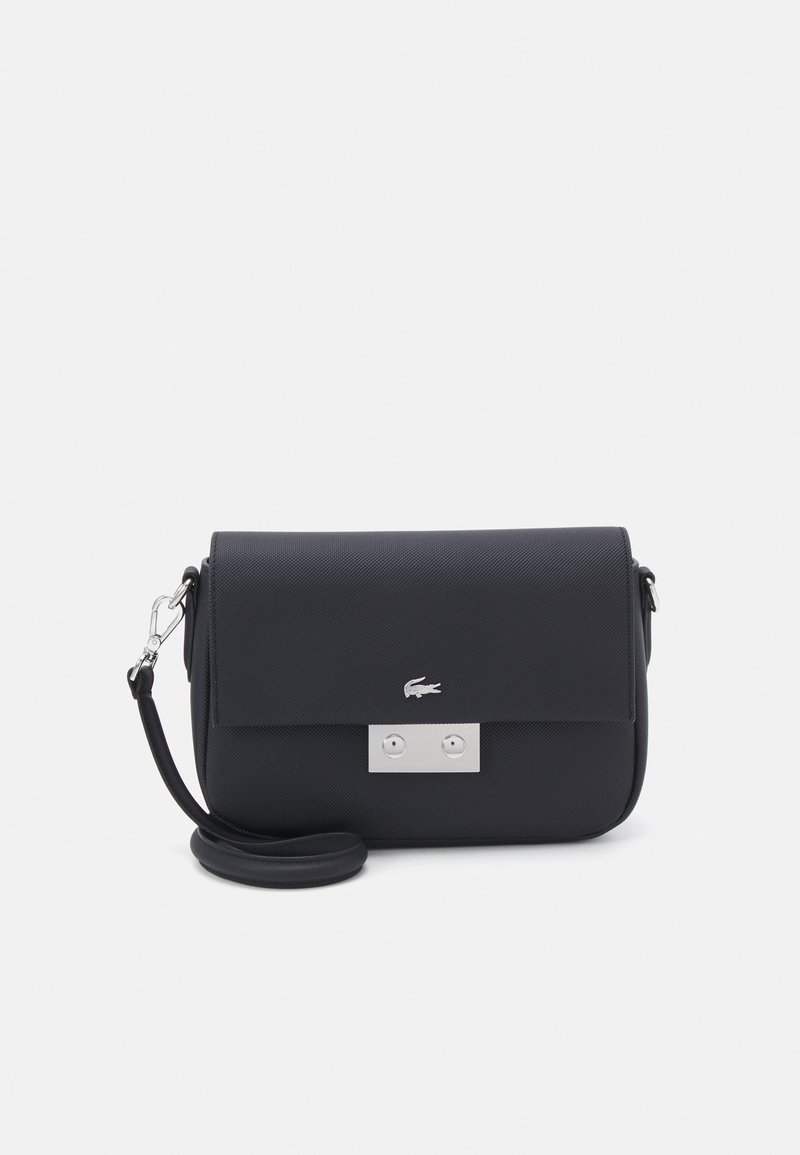 Sac de crossbody synthétique noir avec un fermoir rabat, quincaillerie en argent et surface texturée. Comprend un détail de logo et une bandoulière ajustable.