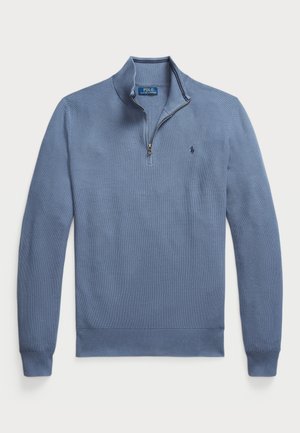 Suéter azul claro con cuello con cremallera, puños y dobladillo acanalados, que presenta un patrón texturizado y un pequeño logotipo en el lado izquierdo del pecho.