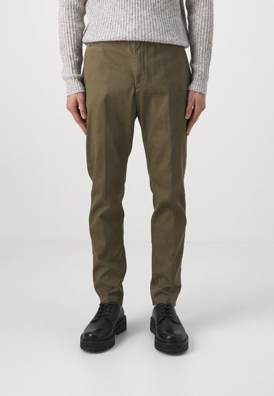 Olijfgroene broek van katoenmix, met een rechte snit en zijzakken, gecombineerd met zwarte veterschoenen.