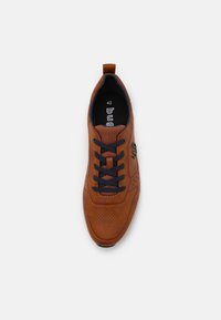 Baskets en cuir perforé marron avec des lacets bleu marine et un onglet de talon en boucle, présentant un logo et une étiquette de taille à l'intérieur de la chaussure.