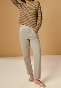 Gestreepte bruin lange mouwen top, gecombineerd met lichtgrijze rechte jeans en beige hakken flip-flops. Glad textuur en casual pasvorm.