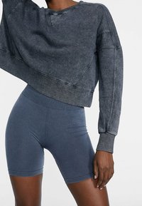 Czarnoszary krótkowy sweatshirt o fakturowanym wykończeniu i ściągaczach, zestawiony z granatowymi szortami kolarskimi z bezszwowym pasem.