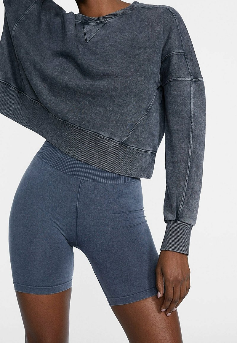 Czarnoszary krótkowy sweatshirt o fakturowanym wykończeniu i ściągaczach, zestawiony z granatowymi szortami kolarskimi z bezszwowym pasem.