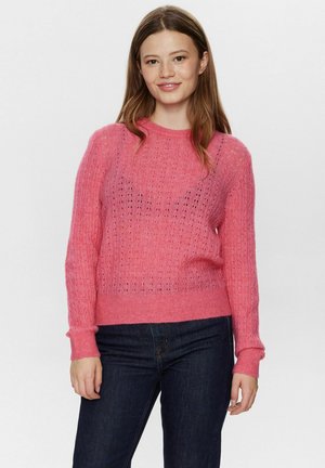 Maglione rosa lavorato a maglia con un motivo testurizzato, scollo rotondo e maniche lunghe. Abbinato a jeans in denim scuro.