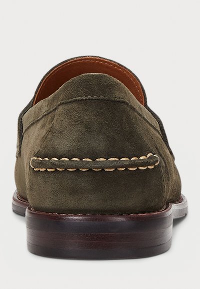Πράσινα μοκασίνια από σουέντ με κυρτή πίσω όψη, επένδυση από δέρμα σε αντίθετο χρώμα και λευκά διακοσμητικά ράμματα κατά μήκος της ραφής σε σκοτεινή ξύλινη σόλα.