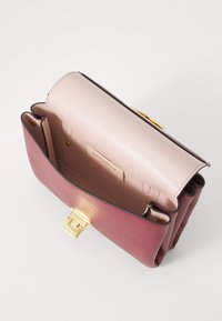 Struktureret håndtaske i bordeaux og pink læder med en glat tekstur. Har en guldlås og et indre mærke.
