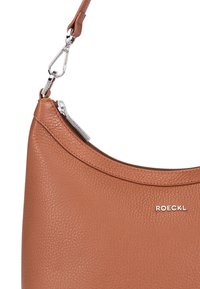 Braune Leder-Schultertasche mit strukturierter Oberfläche, geschwungener Form, Reißverschlüssen und einem silberfarbenen Hardware-Akzent mit Markenlogo.