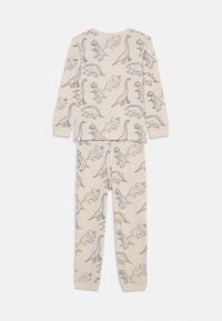 Baumwoll-Pyjama-Set mit langen Ärmeln und Hosen. Hellbeige mit schwarzen Dinosaurier-Illustrationen. Glatte Textur, lockere Passform.
