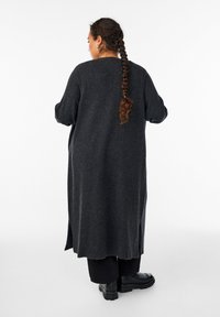 Langer, dunkelgrauer Strickcardigan mit Seitenschlitzen und lockerer Passform. Er hat einen runden Ausschnitt und volle Ärmel. Glatte Textur.