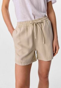 Beige shorts med elastisk talje og snor, med sidelommer og et glat, letvægtsstof. Casual fit og enkelt design.