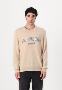 Beige genser med lange ermer og ribbede mansjetter, med et grafisk design "FUTURE PARIS" i svart. Myk tekstur, rund hals.