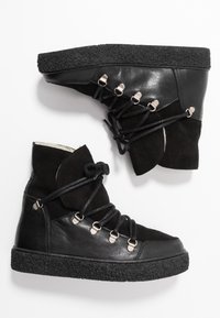 Černé kožené a semišové vysoké sneakers s kulatou špičkou, texturovanými gumovými podrážkami, kovovými očky a nastavovacími šněrovadly pro bezpečné uchycení.