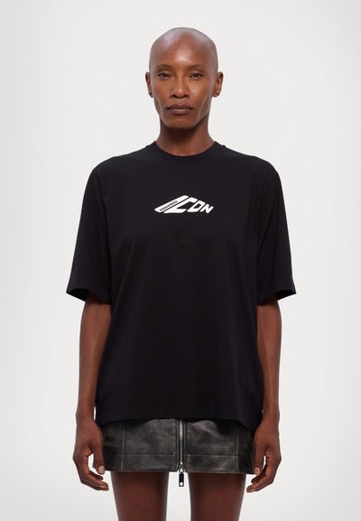 T-shirt noir à manches courtes en coton, arborant un logo graphique blanc sur la poitrine. Coupe ample avec un col rond.