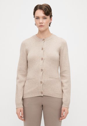 Beige cardigan tillverkad av mjukt stickat tyg. Har rund hals, knappstängning fram, två fickor samt ribbade muddar och fåll.
